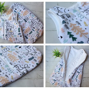 May include: White baby sleep sack with a whimsical pattern of unicorns, trees, and clouds in pastel colors. The sleep sack has a full-length zipper and a sleeveless design. The fabric appears soft and comfortable, suitable for a baby's delicate skin.