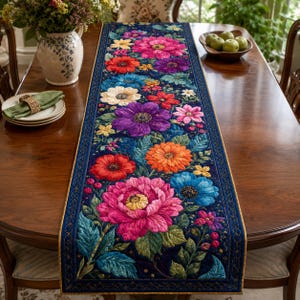 May include: A rectangular quilted table runner featuring a vibrant floral pattern on a dark blue background. The design includes large, textured blossoms in shades of pink, purple, orange, red, and blue, accented with green leaves and small berries.