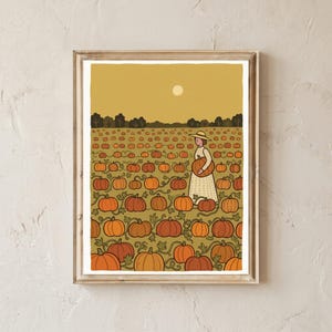 May include: A framed art print featuring a flat illustration of a vast pumpkin patch under a golden yellow sky with a pale sun. A figure wearing a wide-brimmed hat and a long, light-coloured dress stands in the field, holding a single orange pumpkin.