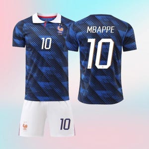 以下が含まれることがあります： 白い襟が付いたダークブルーのサッカーユニフォーム。斜めのストライプ柄、背番号10、雄鶏のエンブレムが特徴です。背中には「MBAPPE」の名前と背番号10がプリントされています。背番号10が入った白いサッカーショーツも含まれています。