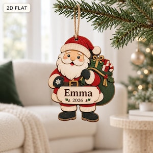May include: A flat wooden Christmas ornament shaped like Santa Claus wearing a red suit and hat, carrying a green sack of gifts. A white banner across the center features the name Emma and the year 2026. The ornament hangs from a jute twine loop.