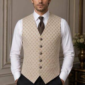 May include: A beige waistcoat featuring a repeating diamond pattern in gold and brown, a V-neckline, and five round metallic buttons down the front. The garment is worn over a crisp white long-sleeved button-down shirt with a dark brown necktie.
