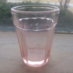 May include: A clear, pink glass shot glass with a fluted design.
