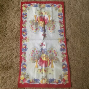 May include: A vintage red and white tea towel with a colorful illustration of two people picking apples from trees. The border features a repeating pattern of apples, pears, and berries.