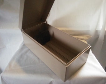 May include: A beige metal box with a hinged lid that is open. The box is empty.