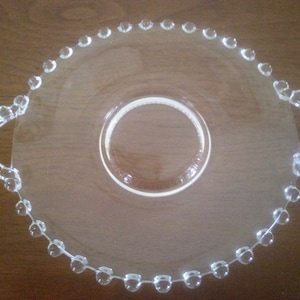 May include: A clear glass serving tray with beaded edges and two handles. The tray has a raised center section.