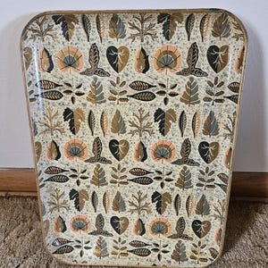 May include: Vintage rectangular tray with a repeating leaf pattern in shades of brown, black, and peach on a cream background. The tray has a gold-colored trim. The tray is likely made of metal or a similar material.