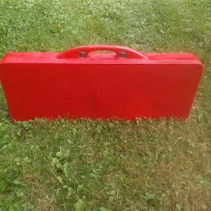 May include: A red folding table and chairs set in a closed carrying case. The case has a handle on top.