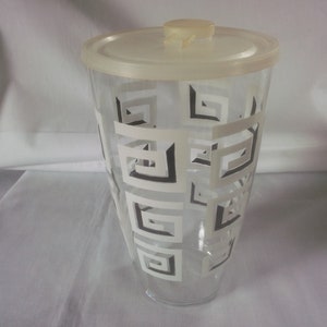 May include: A clear glass pitcher with a white plastic lid. The pitcher has a geometric pattern of black and white squares.