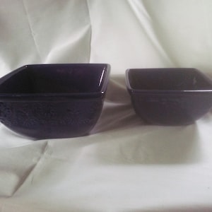 May include: Two square ceramic bowls in a deep indigo blue color. The larger bowl has a decorative pattern on the bottom.
