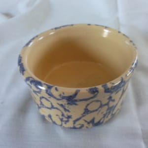 May include: A small, white ceramic bowl with a blue and white floral pattern. The bowl is empty and has a smooth, rounded interior.