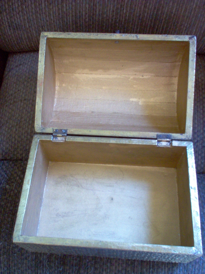 May include: An open, rectangular wooden box with a hinged lid. The box is painted gold on the exterior and has a light brown interior. The box is empty and appears to be made of wood.