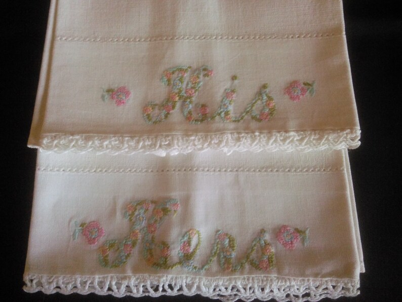 May include: Two white pillowcases with embroidered floral lettering, one says "His" and the other says "Hers".