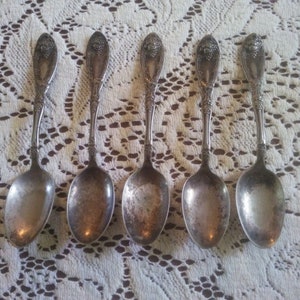 May include: Set of six silver spoons with ornate handles. The spoons have a grape design on the handles and are in good condition.