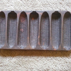 May include: Cast iron cornbread pan with eight individual molds. The pan is dark gray and has a rustic look.