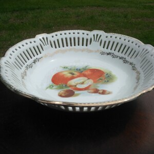 May include: White porcelain fruit bowl with a cut-out design and a painted image of apples and nuts.