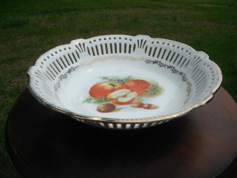 May include: White porcelain fruit bowl with a cut-out design and a painted image of apples and nuts.