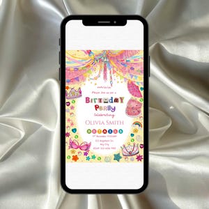 A Fancy Nancy–style birthday invitation displayed on a smartphone, glowing against silky fabric. The design bursts with colorful glitter‑like crowns, hearts, stars, flowers, and bright streamers in pink, yellow, purple, and blue. It feels whimsical, glamorous, and festive, celebrating Olivia Smith with a joyful, sparkly party aesthetic.