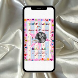 A smartphone rests on a surface while displaying a bright, playful birthday invitation. The design features pastel stripes with stars, hearts, smiley faces, flowers, and other fun sticker‑style decorations. In the center, a round black‑and‑white photo of a smiling child appears beside a cute birthday cake illustration. The overall look is colorful, crafty, and whimsical, perfect for a child’s celebration.