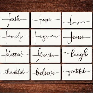 May include: A collection of white rectangular stencils with black cursive text. The stencils feature words like "faith," "hope," "love," "family," "forgiven," "Jesus," "blessed," "strength," "laugh," "thankful," "believe," and "grateful."