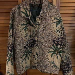 May include: A brown and green quilted jacket with a palm tree print. The jacket has a button closure and a collar.