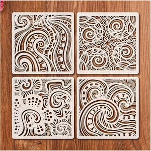 May include: Four square wooden stencils with intricate, repeating patterns. Each stencil features a unique design of swirling lines, circles, and organic shapes, cut out to create negative space. The stencils are light brown and sit on a wooden surface.