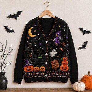 May include: A black V-neck cardigan featuring a button-down front and embroidered Halloween motifs including a yellow crescent moon, a purple-clad witch on a broomstick, a black cat, a white ghost, pumpkins, and a sign reading Spooky Vibes Only.
