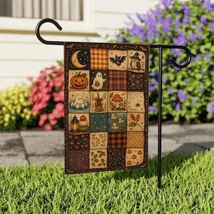 May include: A rectangular garden flag hanging on a black metal stand, featuring a patchwork design with various autumn and Halloween motifs including a crescent moon, a jack-o'-lantern, ghosts, a bat, an owl, mushrooms, and small rubber ducks.
