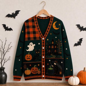 May include: A dark green V-neck button-down cardigan featuring a Halloween-themed knit pattern. The design includes an orange and black plaid panel, a ghost, a black cat, pumpkins, a haunted house, a crescent moon, stars, and a witch with a cauldron.