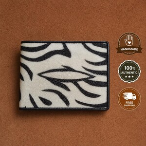 May include: A rectangular bi-fold wallet featuring a textured white surface with a black zebra stripe pattern. The wallet has a solid black border along all four edges. The design is consistent across the front panel of the accessory.