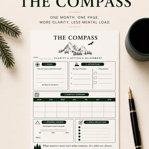 Peut inclure: Une page de planificateur blanche intitulée THE COMPASS avec une illustration de montagne, des sections pour la vision, le plan d'action, l'aperçu mensuel, le suivi des progrès, les victoires et réflexions. Le texte indique : One month. One page.