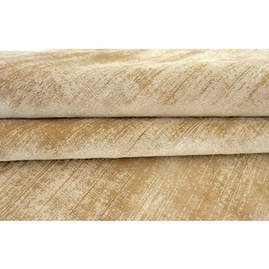 May include: A folded textile with a textured surface in a light golden tan colour. The fabric features a subtle, diagonal, cross-hatched pattern with lighter cream-coloured highlights that create a shimmering, multi-dimensional appearance.