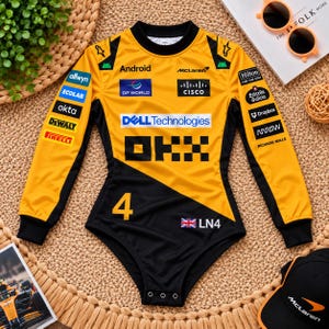 Puede incluir: Un body de manga larga en amarillo y negro con la marca del equipo de Fórmula 1 McLaren. El frente muestra logotipos de Android, DP World, Cisco, Dell Technologies, OKX, además del número 4, una bandera británica y el texto LN4.
