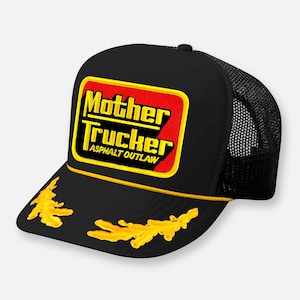 Pode incluir: Um boné trucker preto com um emblema retangular de fundo vermelho e borda amarela. O texto Mother Trucker Asphalt Outlaw está escrito em letras amarelas. A aba é decorada com detalhes bordados em amarelo em formato de folhas.