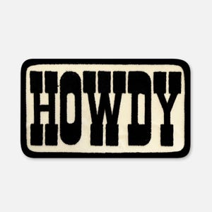 May include: A rectangular embroidered patch with a cream-coloured background and a thick black border. The word HOWDY is stitched in large, bold, black block letters across the centre of the patch, featuring a textured fabric appearance.