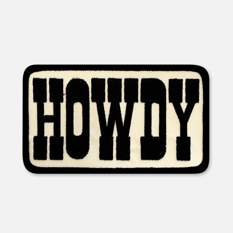 May include: A rectangular embroidered patch with a cream-colored background and a thick black border. The word HOWDY is stitched in large, bold, black block letters across the center of the patch, featuring a textured fabric appearance.
