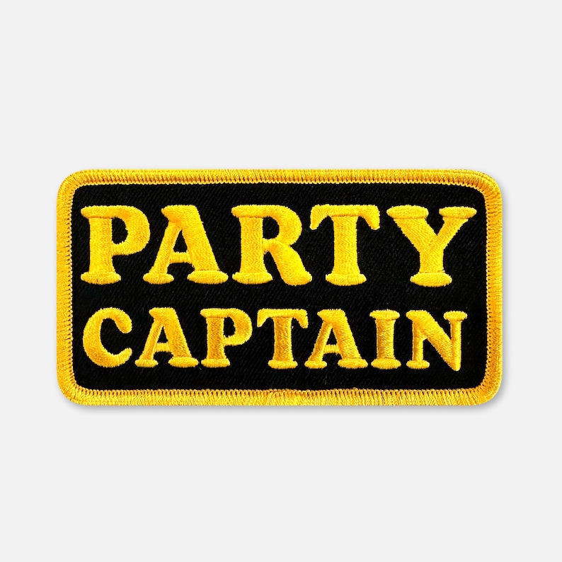 Puede incluir: Un parche rectangular bordado con fondo negro y borde amarillo. El texto PARTY CAPTAIN est&aacute; cosido en letras may&uacute;sculas amarillas en negrita en el centro del parche. El dise&ntilde;o presenta una fuente de estilo bloque clara y definida.