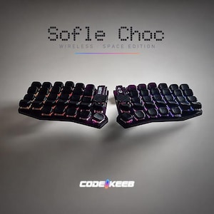 Peut inclure: Un clavier mécanique ergonomique divisé avec des touches noires et un éclairage RVB intégré. Le texte Sofle Choc WIRELESS SPACE EDITION apparaît au-dessus du clavier, et le texte CODE KEEB est centré sous le clavier sur un fond uni.