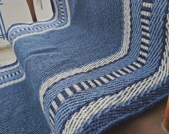 May include: A blue woven stair runner featuring a textured herringbone pattern throughout the center. The runner is accented with vertical stripes in cream and dark blue along the edges, creating a distinct border that follows the stair contour.