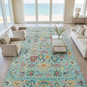 Könnte beinhalten: Ein großer rechteckiger Teppich mit hellblauem Hintergrund und einem sich wiederholenden Muster aus stilisierten Blumen- und geometrischen Motiven in Rosa, Gelb, Dunkelblau und Creme, abgeschlossen mit kurzen weißen Fransen an den Enden.