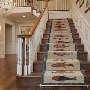 May include: A wooden staircase with a beige carpet runner featuring a repeating pattern of stylized fish in shades of red, blue, and brown. The runner is secured with metallic brass stair rods on each step, set against white wainscoting.