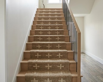 May include: A staircase with light wood treads and a central jute runner featuring a repeating white cross pattern. The stairs include a wooden handrail with vertical black metal balusters, leading upward toward a bright window at the landing.