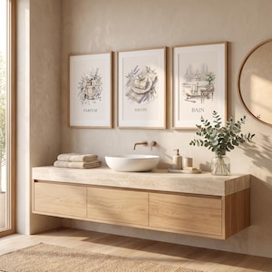 May include: Three framed wall art prints featuring watercolor illustrations of a perfume bottle, a bar of soap, and a bathtub, labeled with the words PARFUM, SAVON, and BAIN, displayed above a light wood floating vanity with a white vessel sink.
