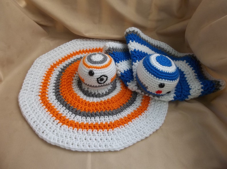 Puede incluir: Una manta de beb&eacute; de crochet blanca, naranja y gris con un personaje BB-8 de crochet blanco, naranja y gris y un personaje BB-8 de crochet azul y blanco.