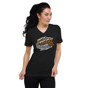 May include: Black v-neck t-shirt featuring the word "Burlesque!" in white and orange text. The text is arranged in a circular design. The shirt is made of a soft material.