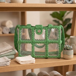 May include: A clear rectangular tote bag featuring a green crocheted grid overlay. The bag includes two green crocheted handles and a central green crocheted tab closure secured with a single silver-toned metal snap button.