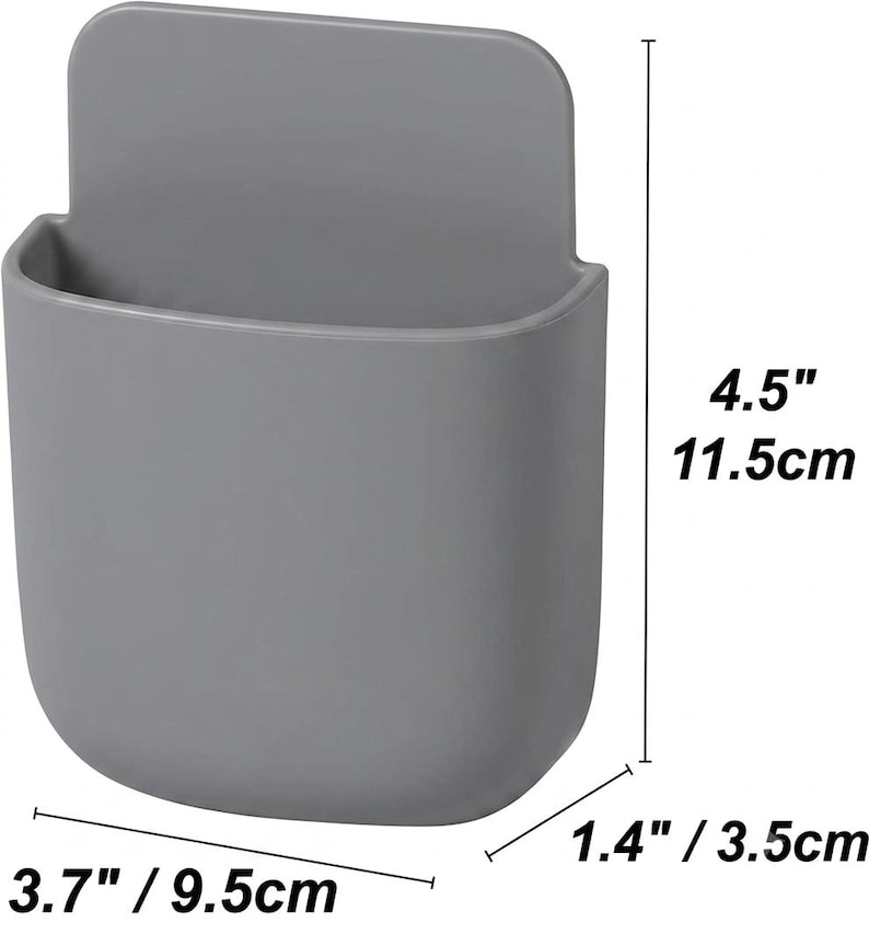 May include: A grey wall-mounted storage pocket with a rounded rectangular shape. The dimensions are clearly marked as 11.5 cm in height, 9.5 cm in width, and 3.5 cm in depth. The container features a smooth, solid-coloured surface.