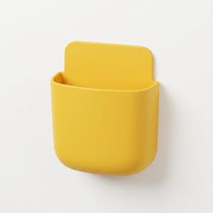 May include: A bright yellow wall-mounted storage pocket with a smooth, matte finish. This U-shaped container features a flat back panel for attachment and a deep, open-top compartment designed for holding small items securely against a flat surface.