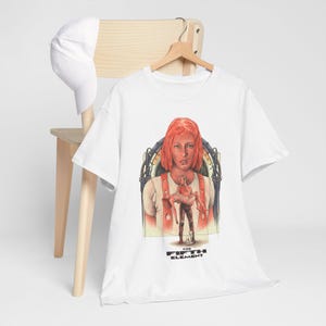 Könnte beinhalten: Ein weißes Kurzarm-T-Shirt mit einem Grafikdruck zum Film Das fünfte Element, das eine Figur mit orangefarbenen Haaren zeigt, die eine andere Person trägt, mit dem Text The Fifth Element unter dem Motiv und einer weißen Baseballkappe.
