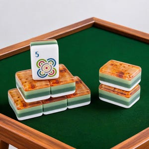 May include: A set of rectangular mahjong tiles featuring a layered design with a white base, a sage green middle section, and a brown burl wood-patterned top. One tile stands vertically, displaying the number 5 and a colorful circular graphic.